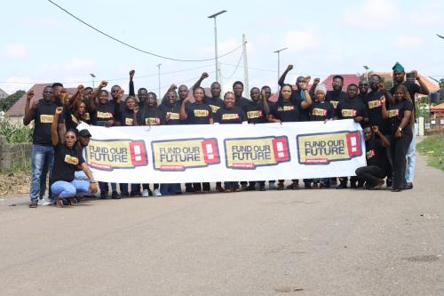 Photo shows a large group of young activists behind a Fund Our Future campaign banner