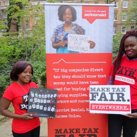 Two women holding posters calling for fair taxation