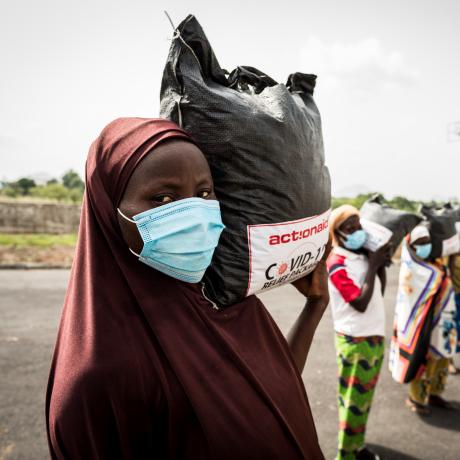 Women from Tungan Nasara community carry their relief packages as they prepare to return to their home