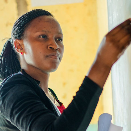 The photo shows a woman writing on a chalkboard