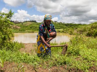 A woman farming with her baby in her arms