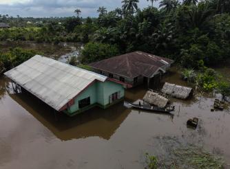 Children use a boat to navigate around their flooded community.