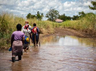 Women farmers walk through flooded fields in Buzi, Mozambique.