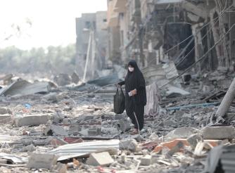 A woman resident of Gaza City searches the rubble for belongings in the aftermath of bombing by the Israeli army.